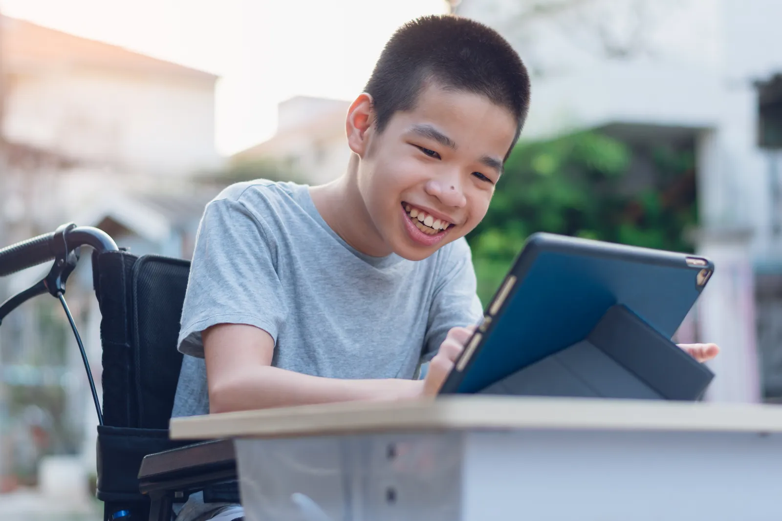 A smiling boy using a communication app on a tablet