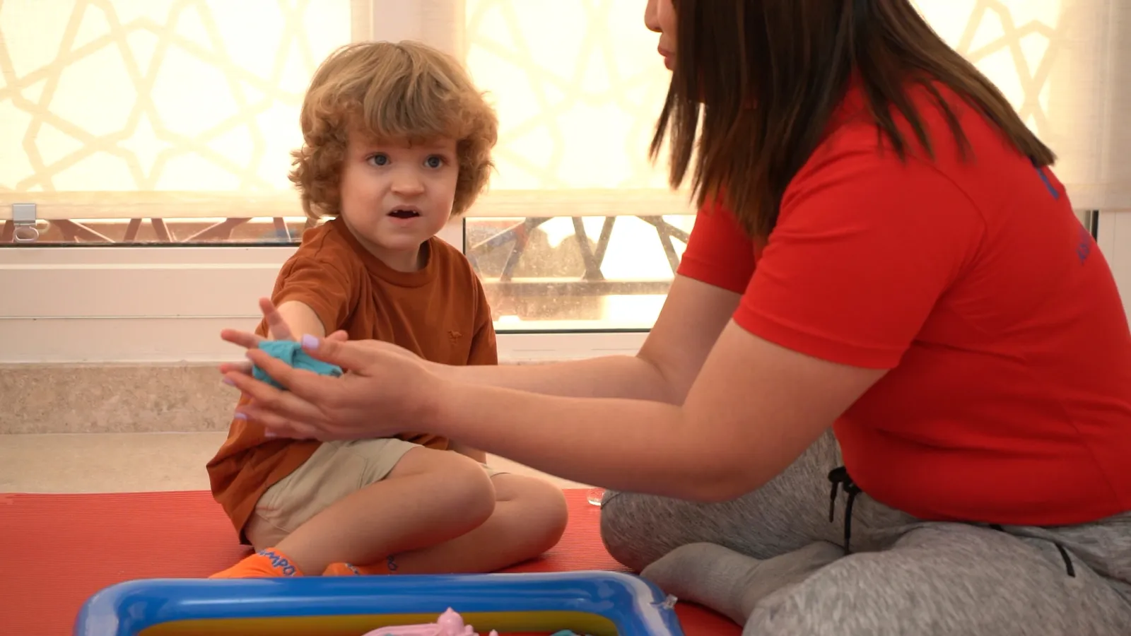 A Hope therapist and a young boy exploring a sensory toy together on the mat