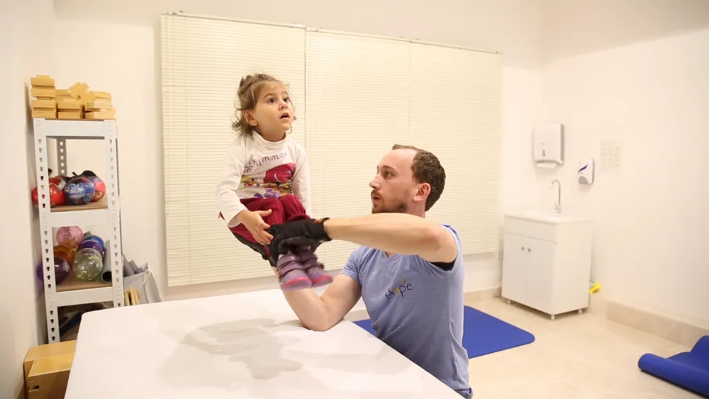 A therapist lifts a child during a balance exercise