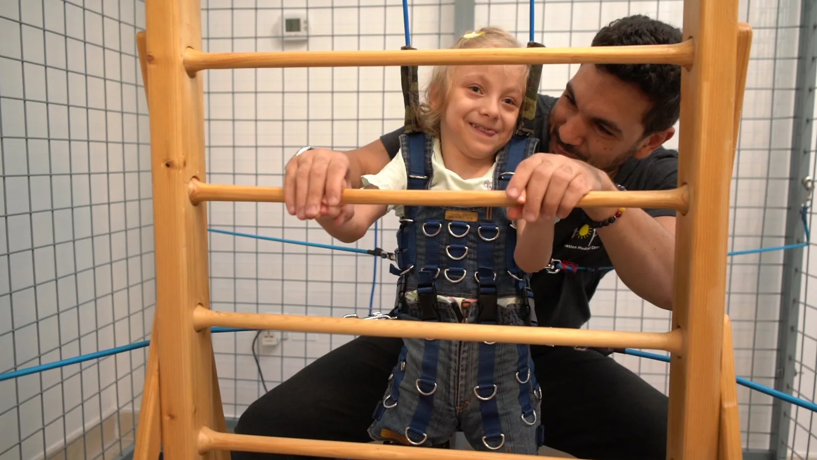 A therapist supports a child at exercise bars