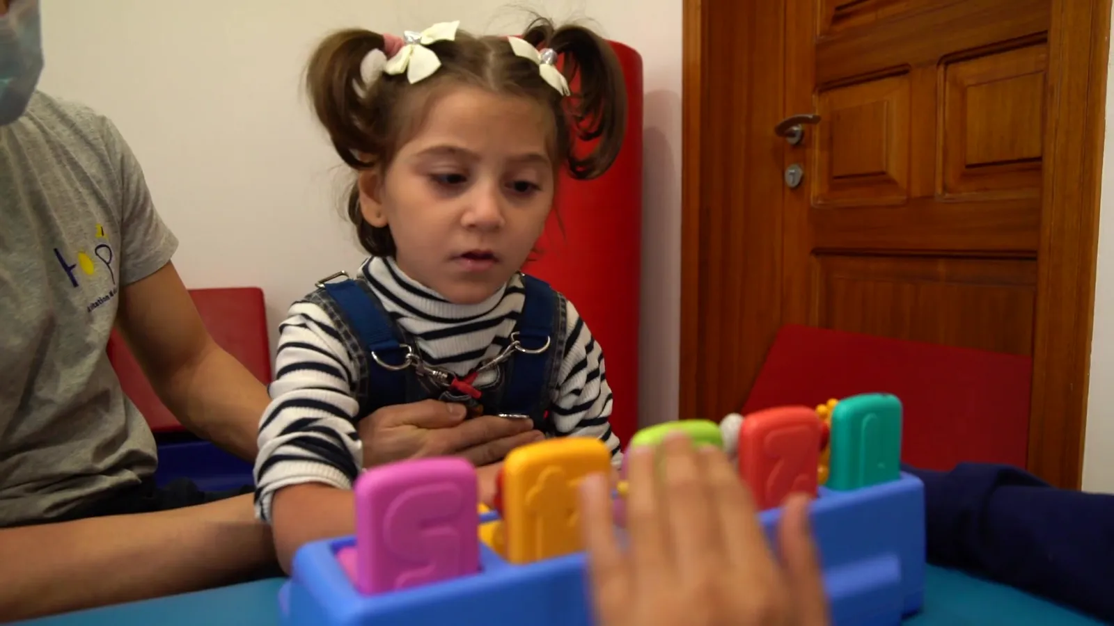 A child plays with a colorful shape sorter during therapy