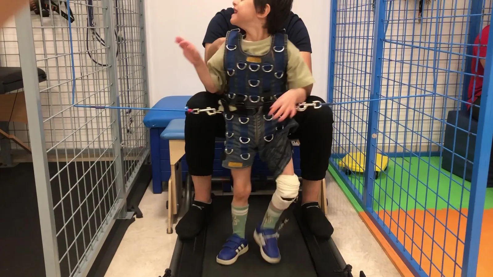 A child wears a therapy suit inside a therapy cage