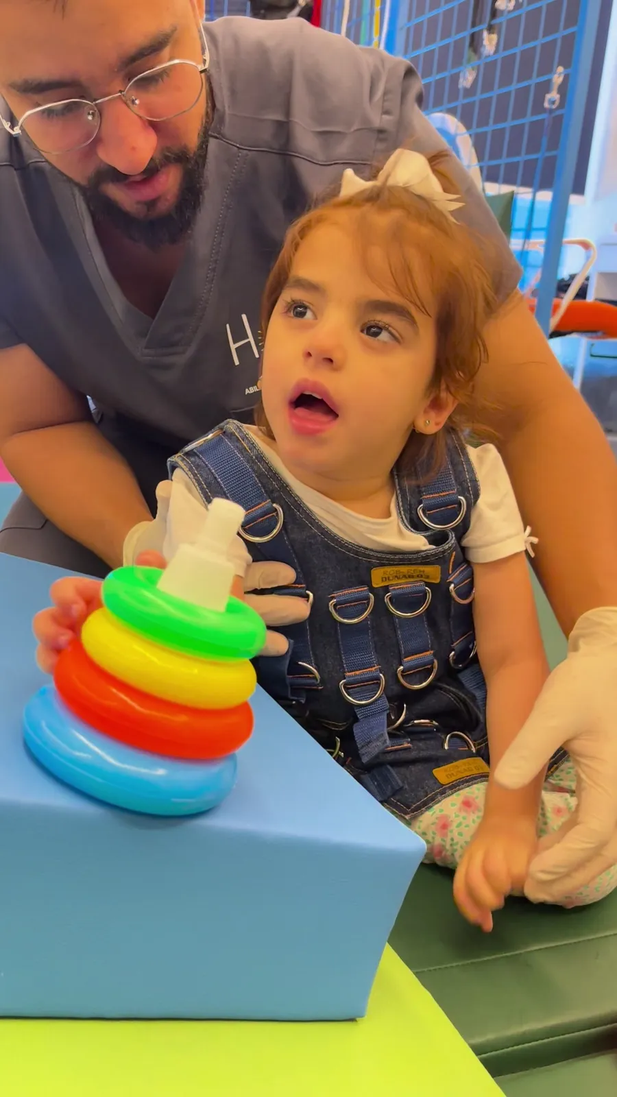 A therapist supports a child stacking rings