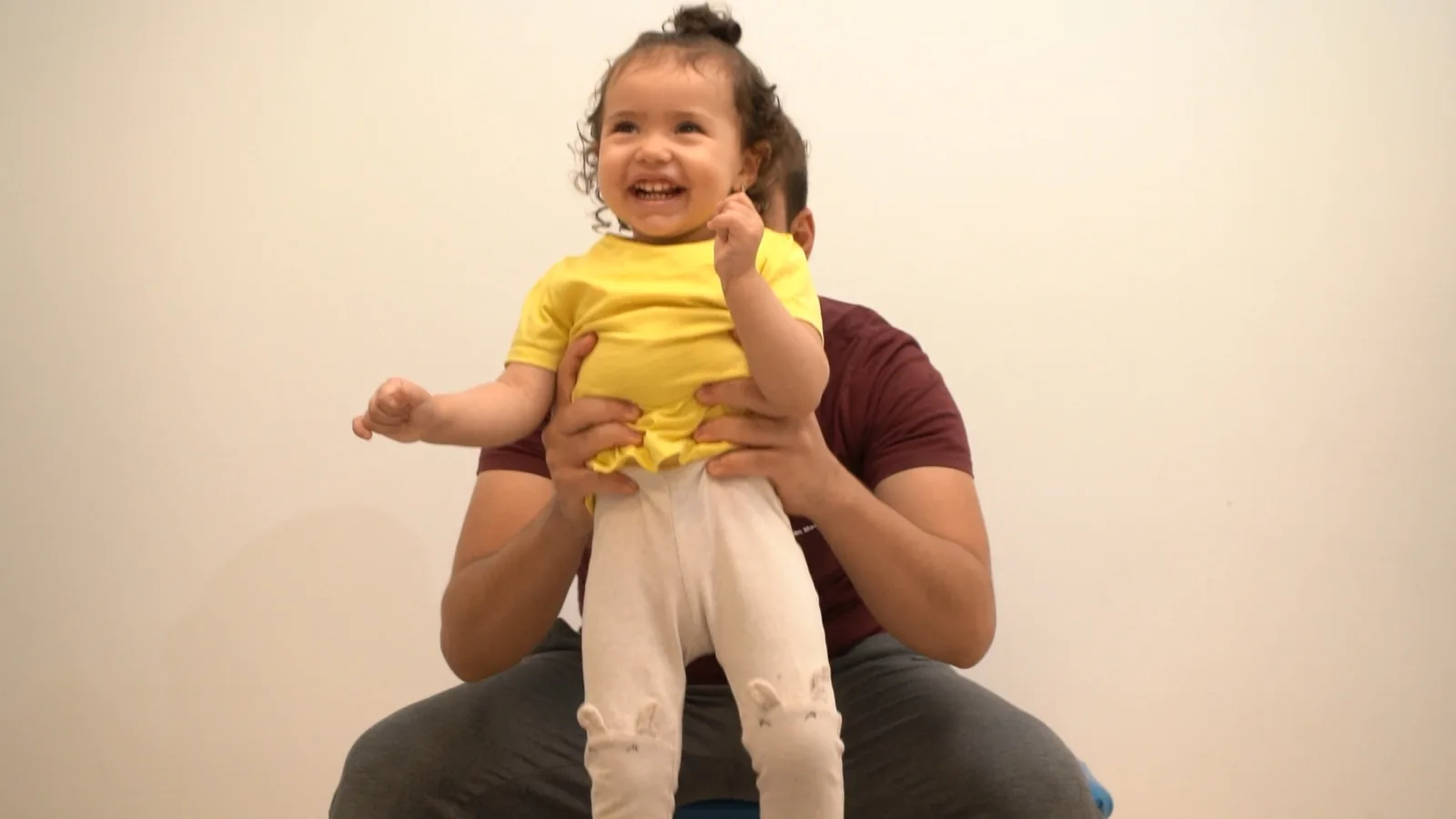 A therapist supports a smiling child during a movement activity