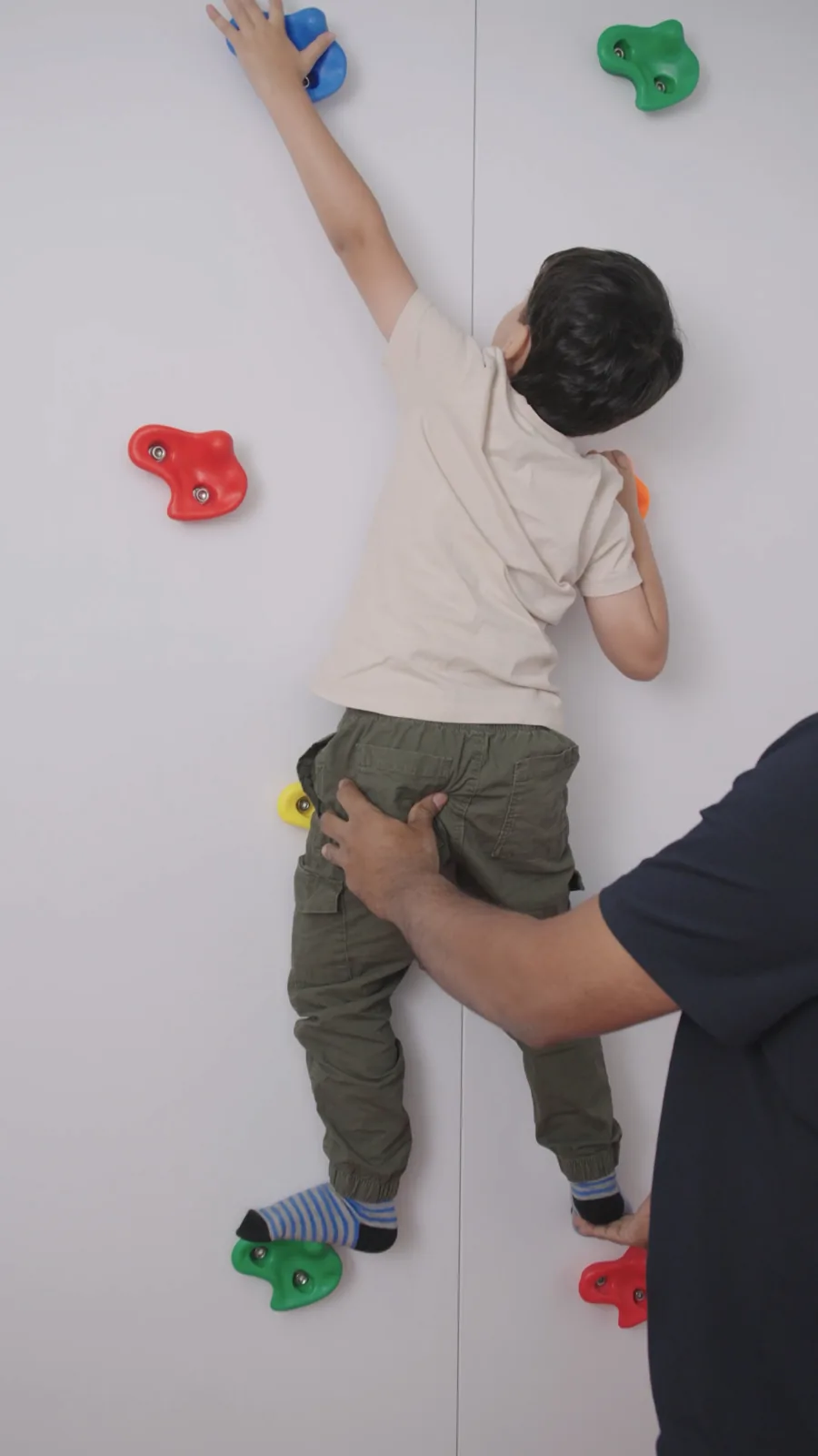 A therapist supports a child on a climbing wall
