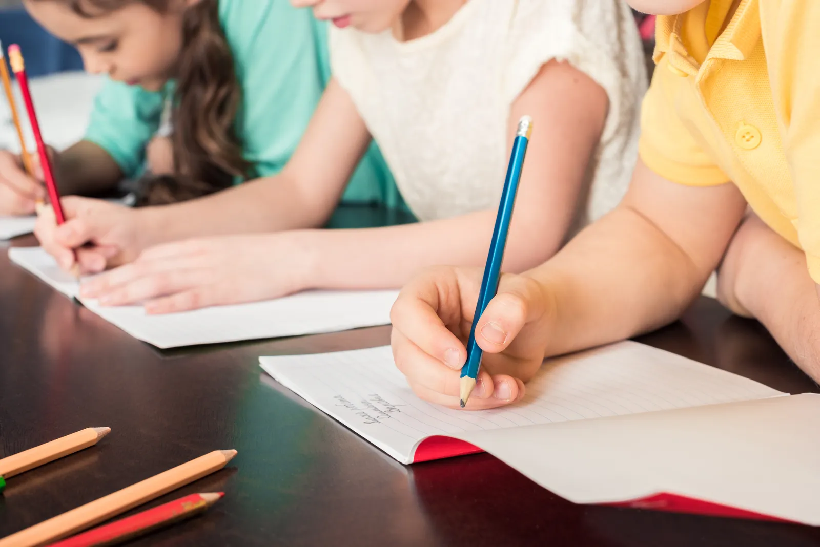 Children practice writing at a table