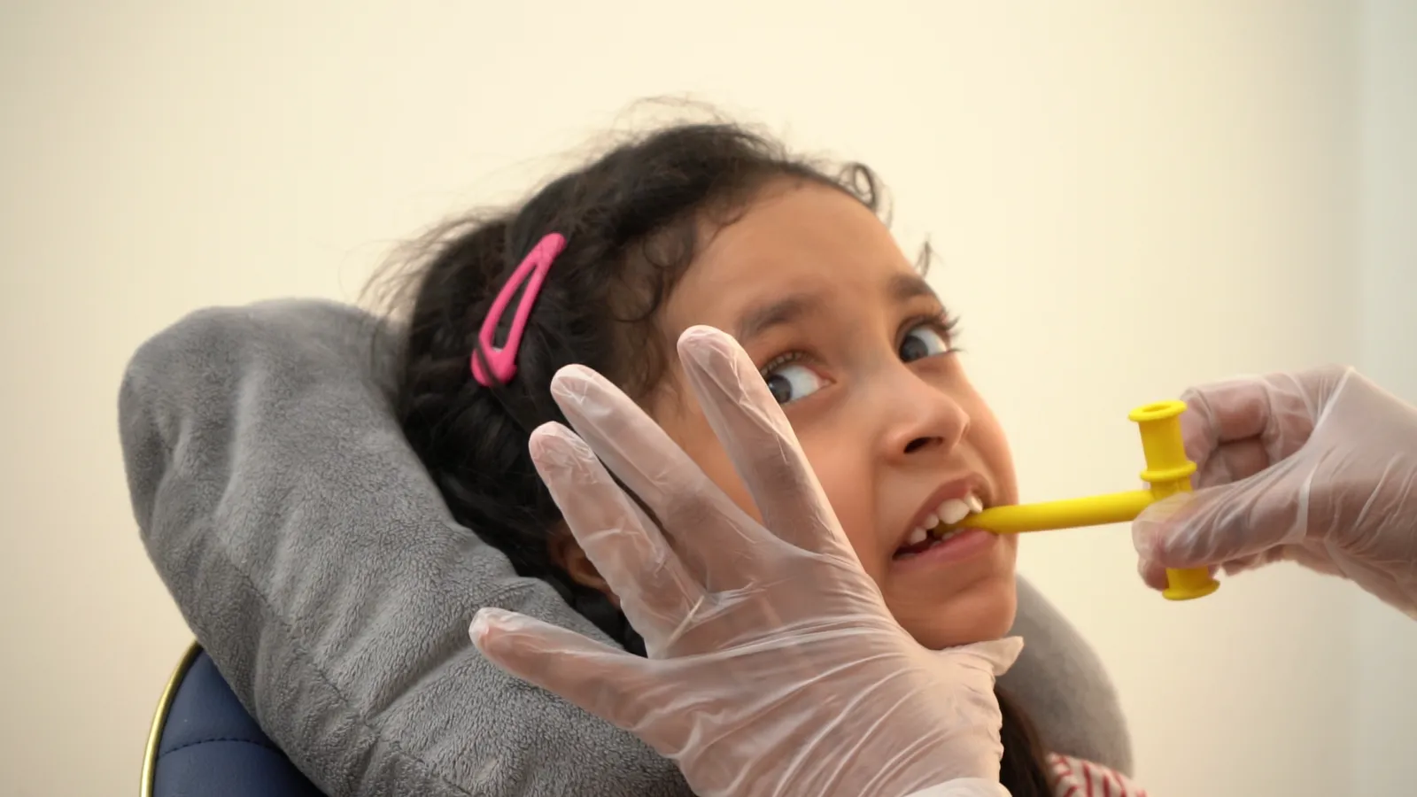 A therapist uses an oral motor tool with a child