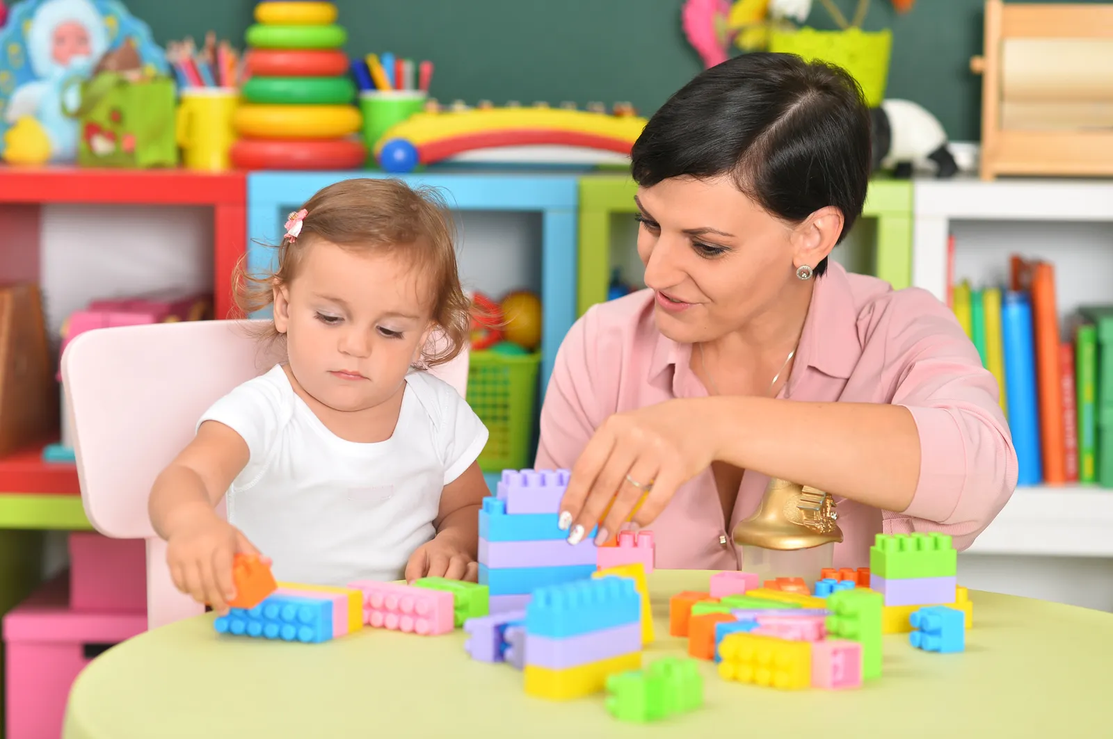 A therapist builds with blocks alongside a toddler