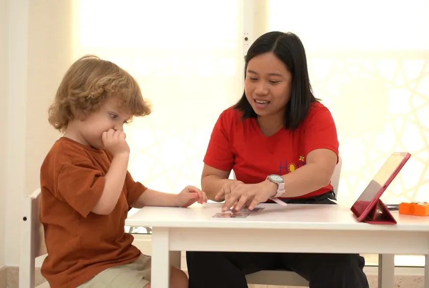 A therapist guides a young boy through a tabletop activity