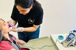 A Hope clinician carries out a check with a girl seated in a supportive chair