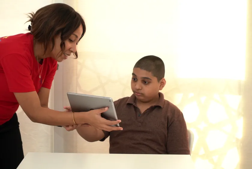 A therapist shows a boy a tablet during a communication session