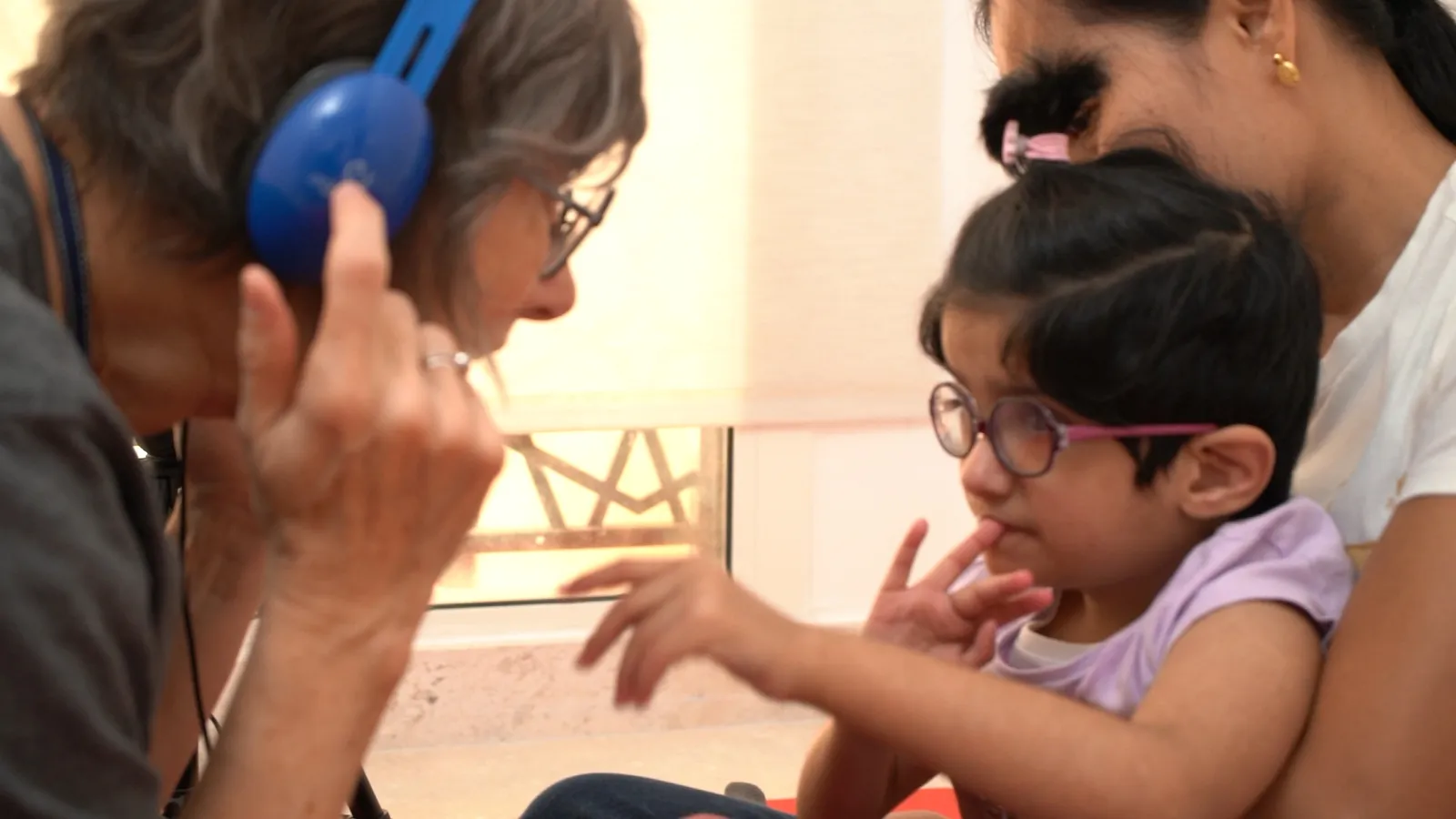 A child explores a listening activity with headphones alongside a therapist