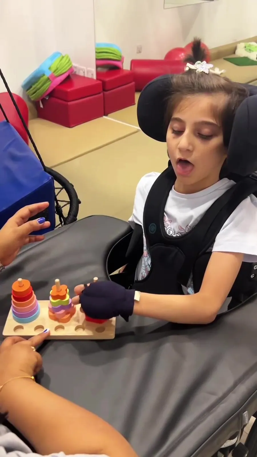 A child plays a fine motor game in a supportive seat
