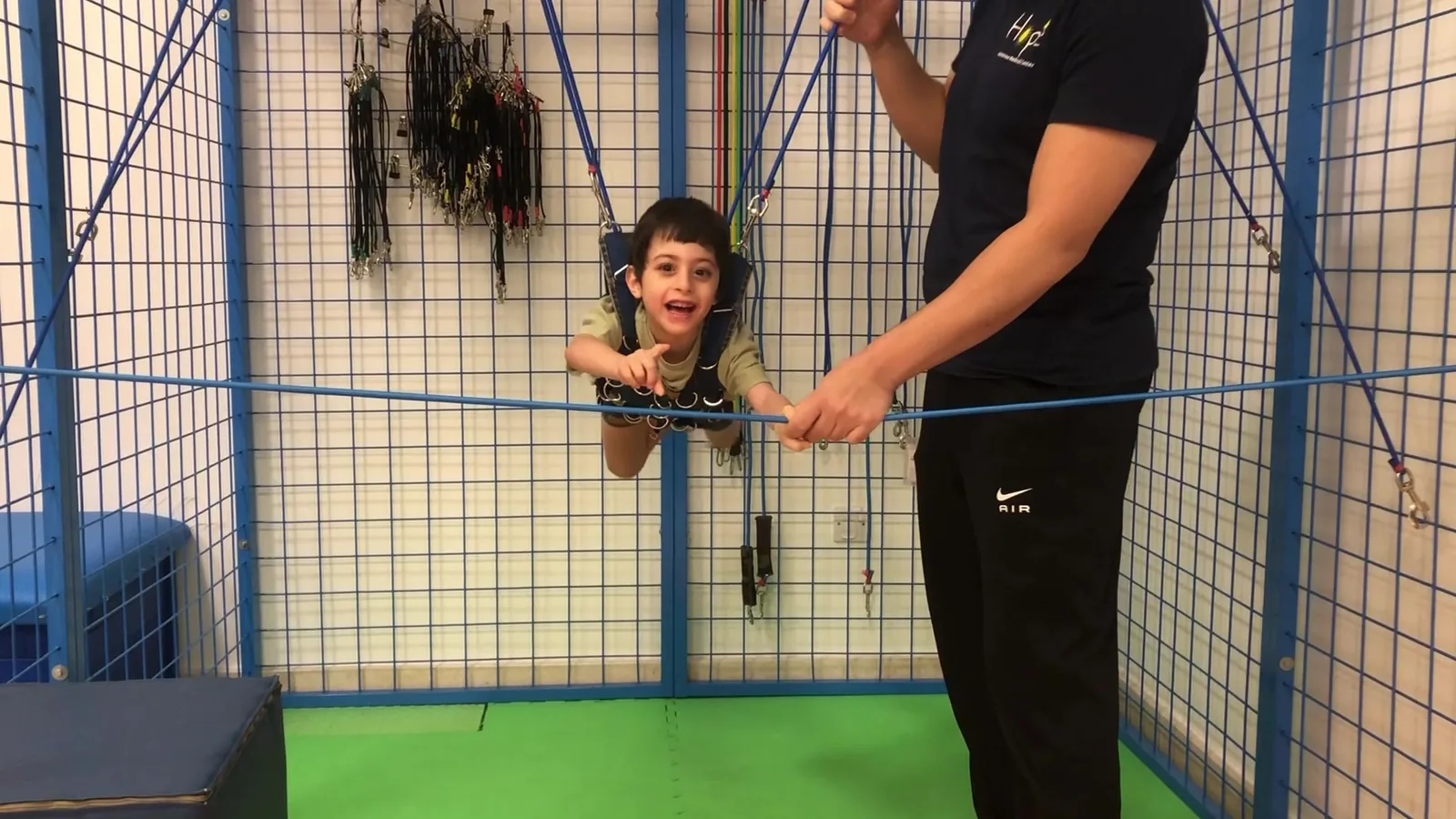 A therapist supports a child using suspension equipment