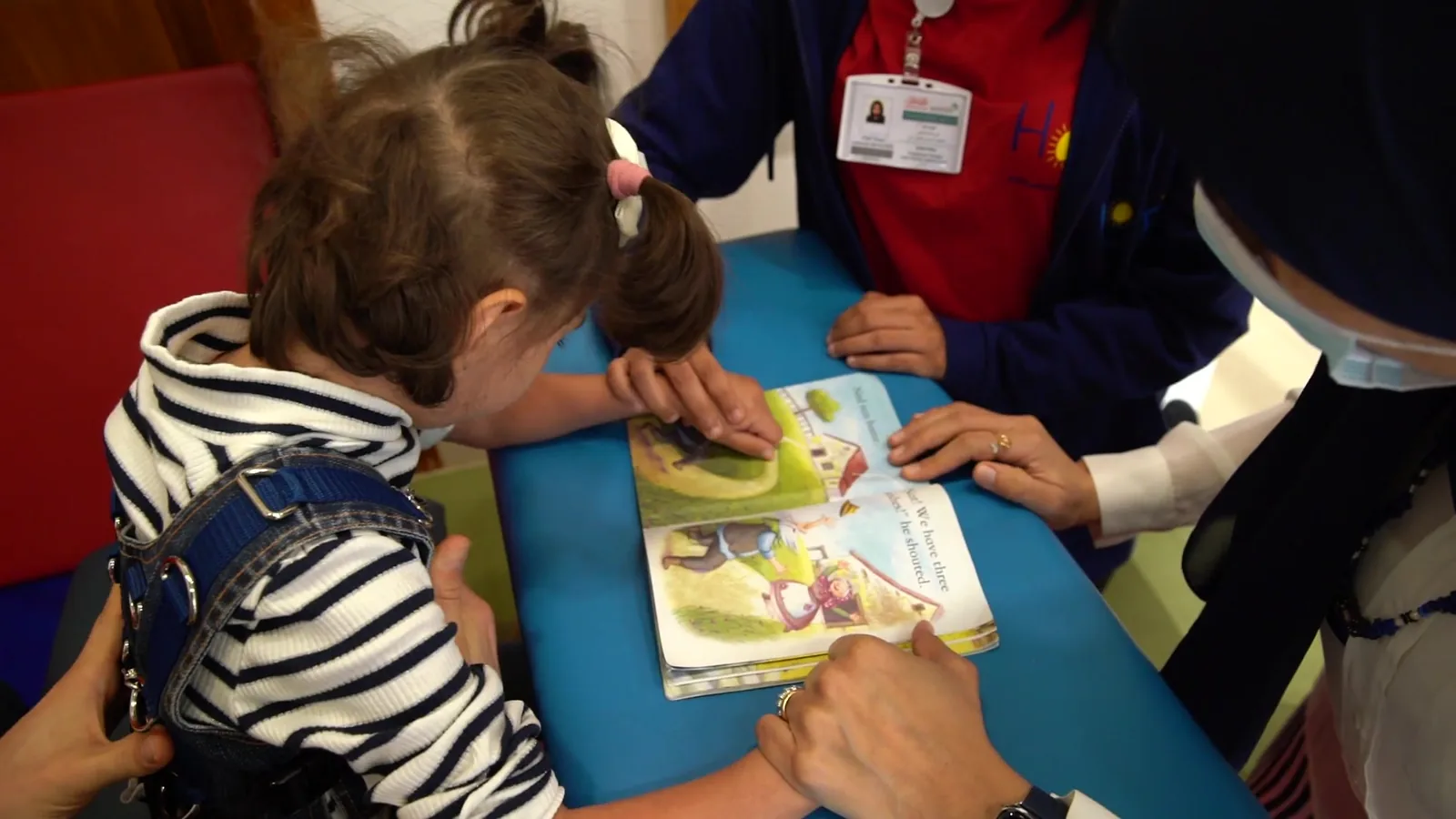 A child explores a picture book with support